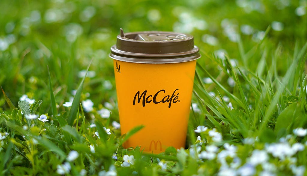 Picture of a McDonalds coffee cup sitting in a grassy field