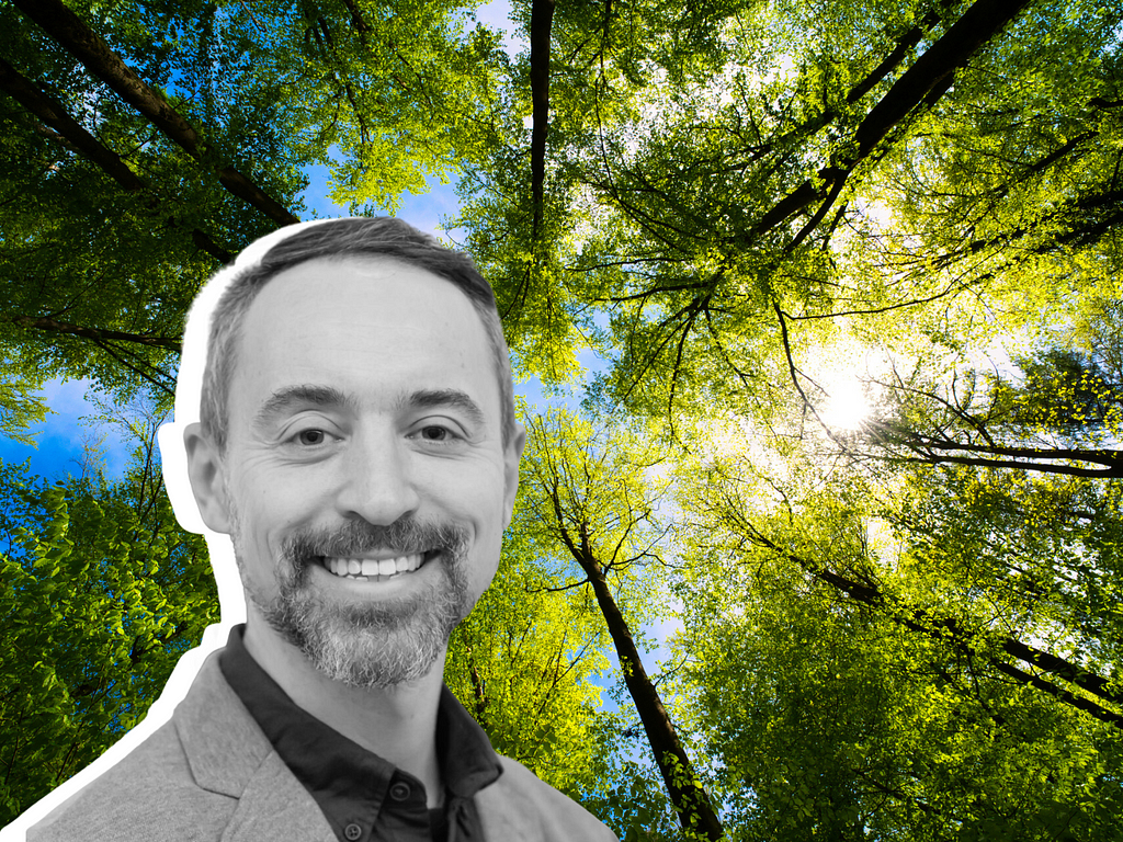 Photo of sunlit trees in the background with a headshot photo of Christopher Rabe in the foreground.