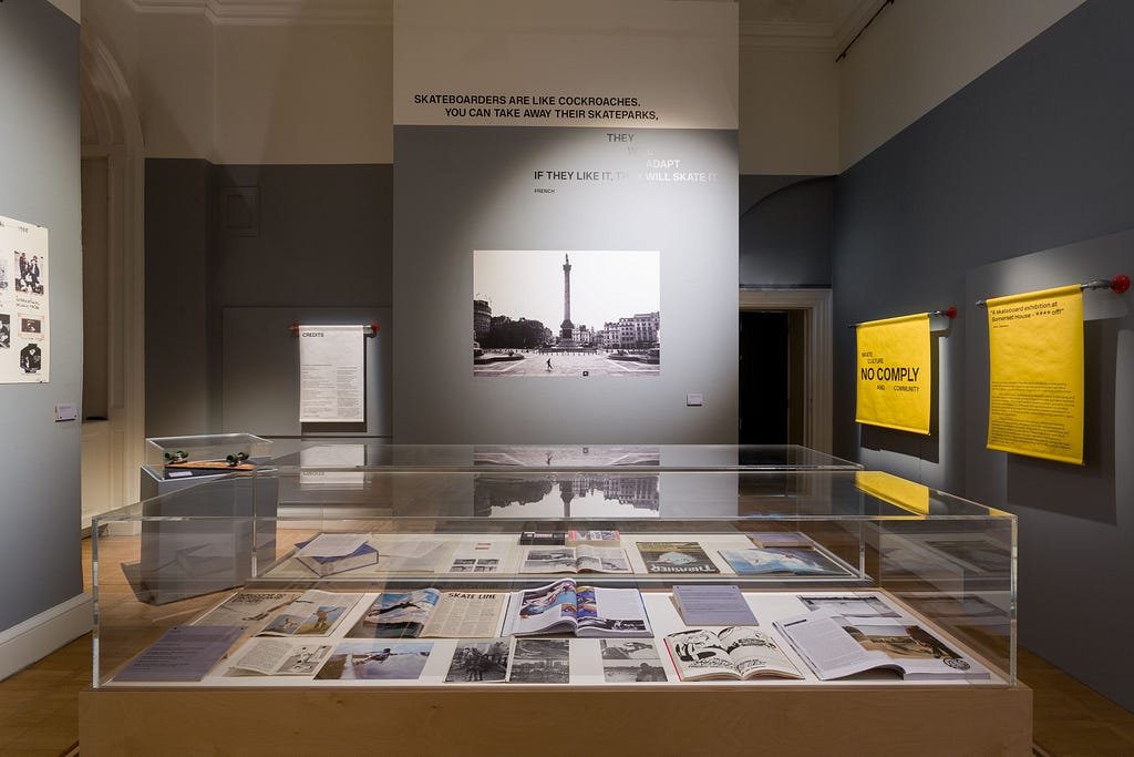 Exhibition room one at Somerset House, numerous cabinets and hanging photographs.