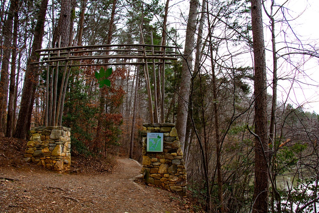 The Alder Trail trailhead, with an archway made of two stone bases and a wooden arch across the top.