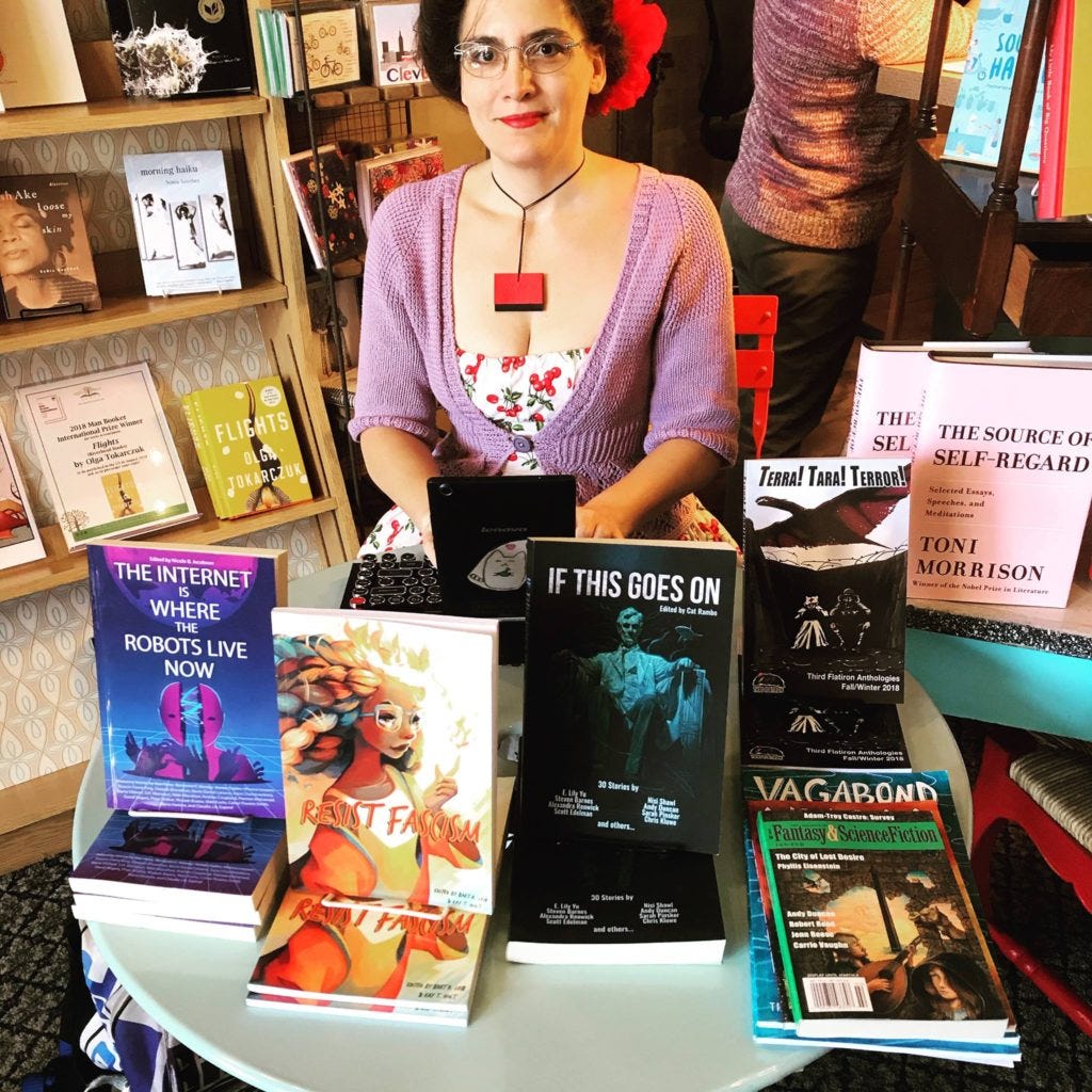 Happy writer at a table in a bookstore surrounded by lots of different books.