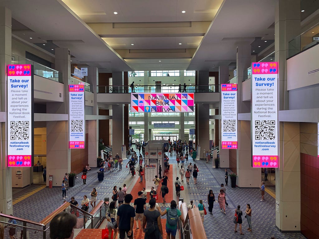 A busy convention center with a “National Book Conference” banner in the background