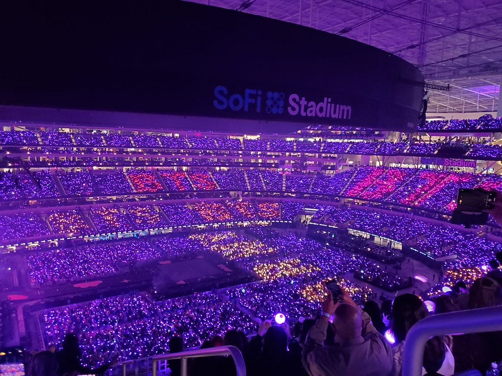 Purple lights illuminated SoFi Stadium, spelling out BTS and ARMY in various shades of pink and purple