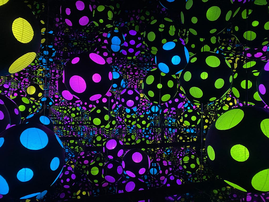 Black orbs in a mirrored room in green, pink, blue and yellow.