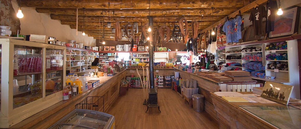 Interior of a trading post in Arizona, with wooden floor and ceiling with various Indigenous artifacts on the walls.