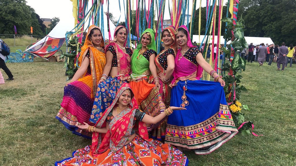 Shine Khrishna poses with five of her Indian dancer pupils. Each is wearing brightly coloured saris. Croydon Mela 2019.