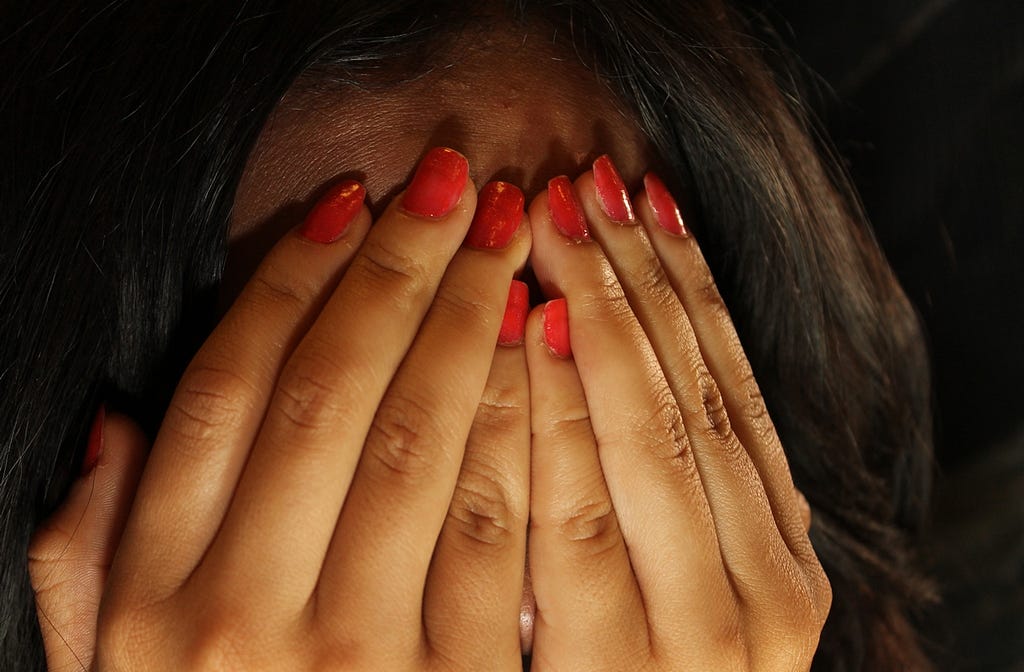 Woman holding her hands over her face in shame