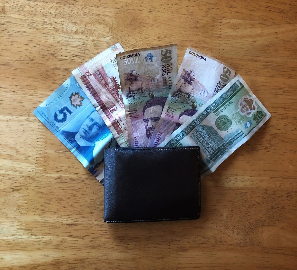 A traveler’s leather wallet containing international dollar bills including Canadian money, Indonesian money, Colombian money