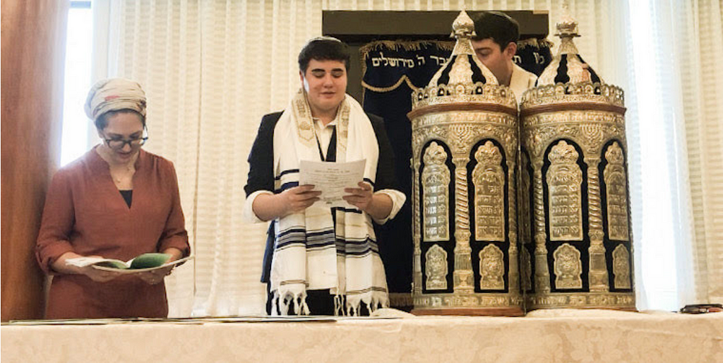 Isaac having a Bar Mitzvah in Israel next to a torah and a woman.