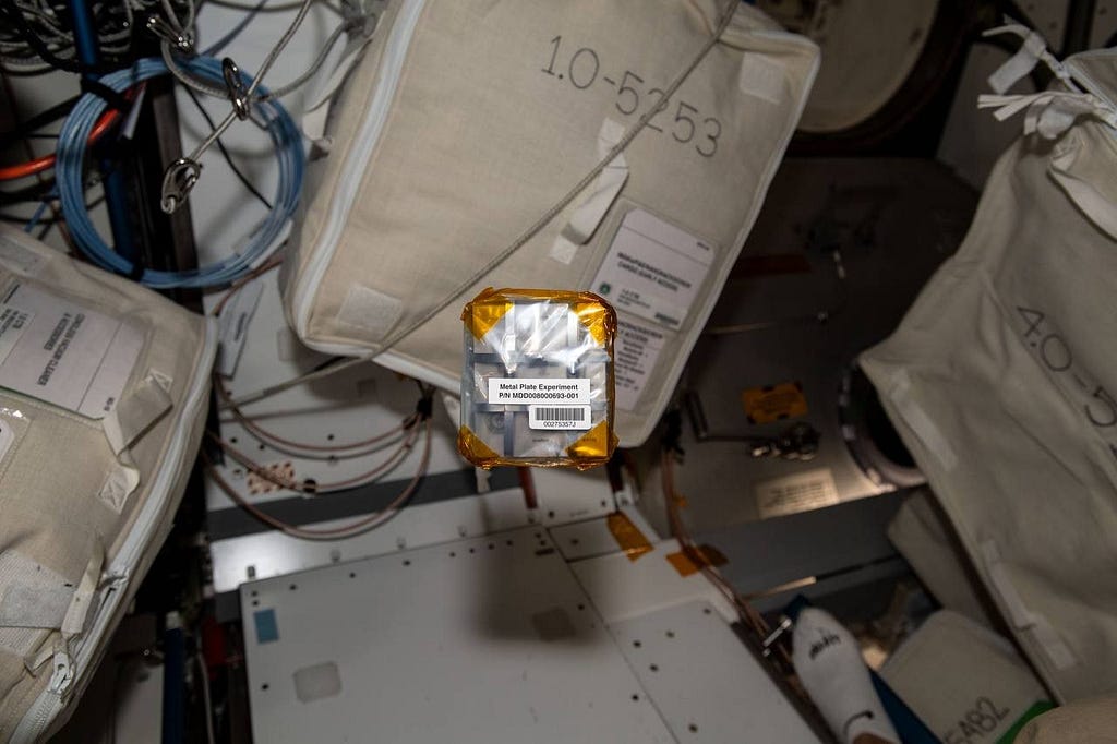 The Project Ascension pack of 25 Titanium plates wrapped in plastic floats aboard the International Space Station.