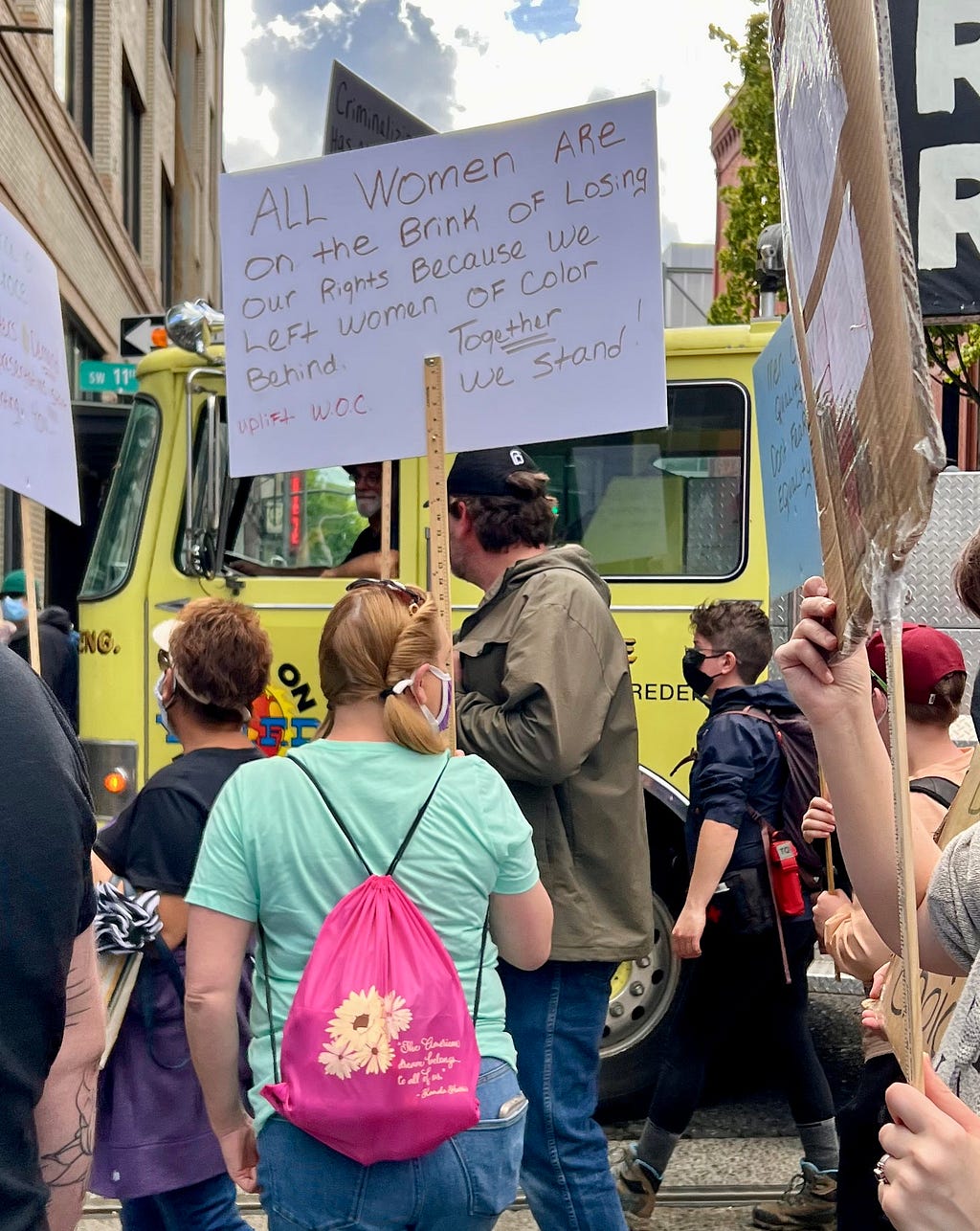 Woman (named Candy) with sign reading: All women are on the brink of losing our rights because we left women of color behind. Together we stand. Uplift WOC