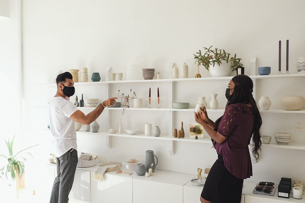 A man and a woman looking at homeware products on a shelf in a store.