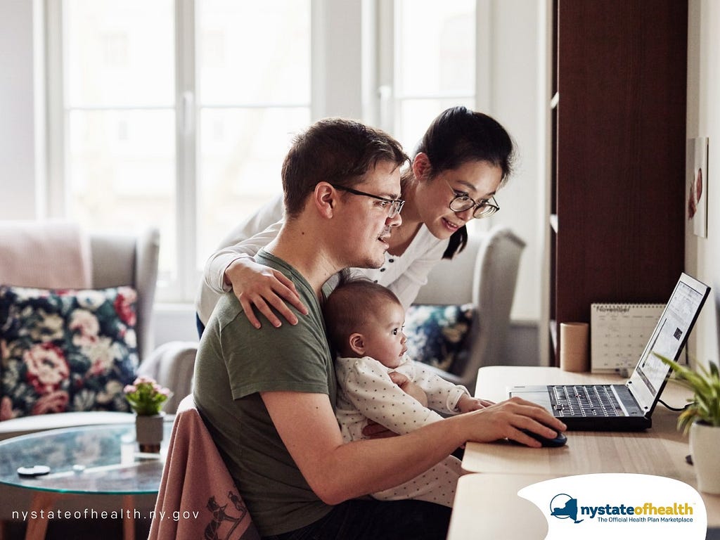 A family huddles around a laptop to learn more about renewing their health insurance coverage.