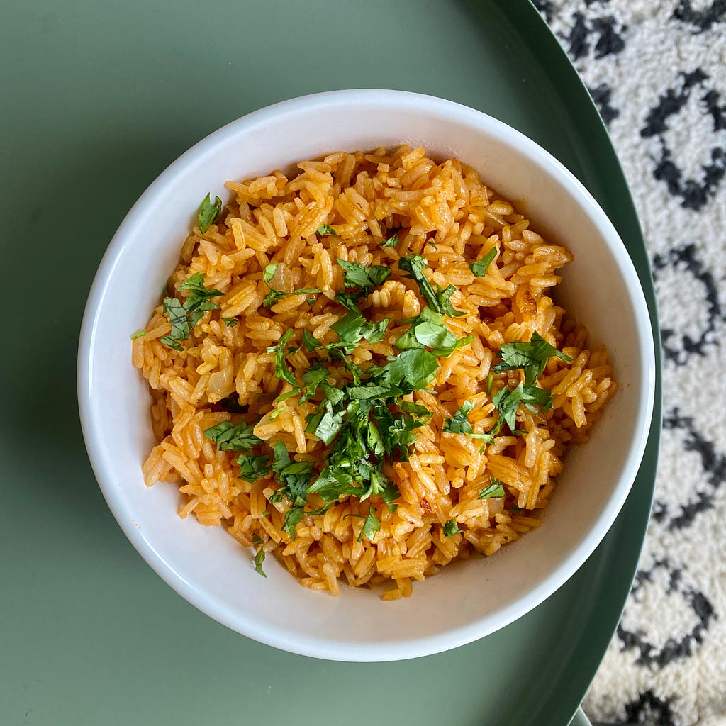 a bowl of Spanish rice garnished with some parsley.