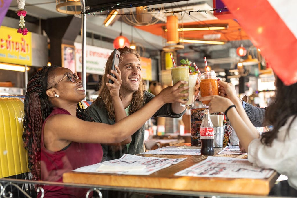 A group of students enjoy a meal out together in central Leeds, they are all raising their glasses to each other and one is taking a picture with their phone.