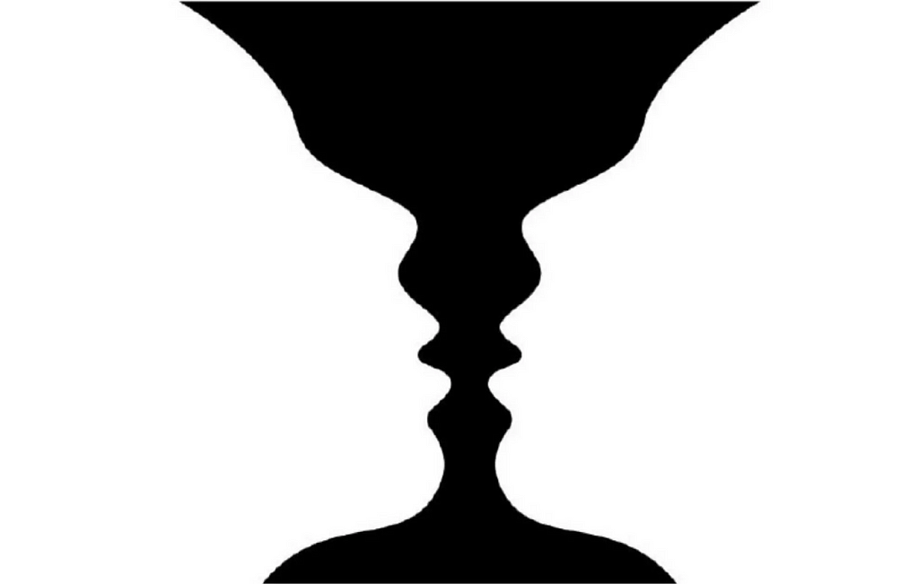 Two white silhouettes of a side profile of a head or face on black background. Because the image is cut in a way, that the heads touch the top, bottom and sides of the image, there’s only black background in the center. This black background mimics another silhouette and looks like a vase.