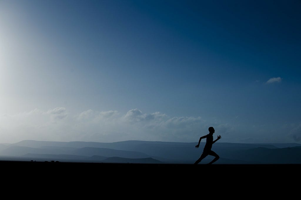 A person running in the evening against a big, blue evening sky.