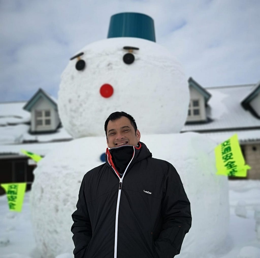 Man standing in front of snowman
