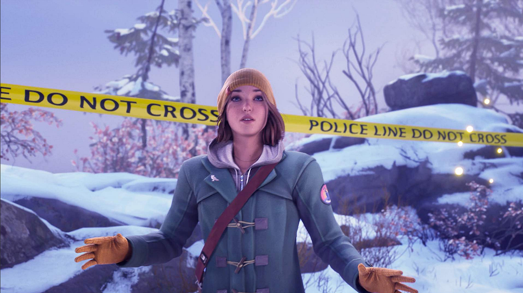 Max in the new game, wearing a yellow beanie, yellow gloves, a green winter coat with a grey hoodie underneath, and the strap for a satchel across her chest. There’s snowy woods behind her, as well as police tape. Her hands are held out, almost in a plea gesture.