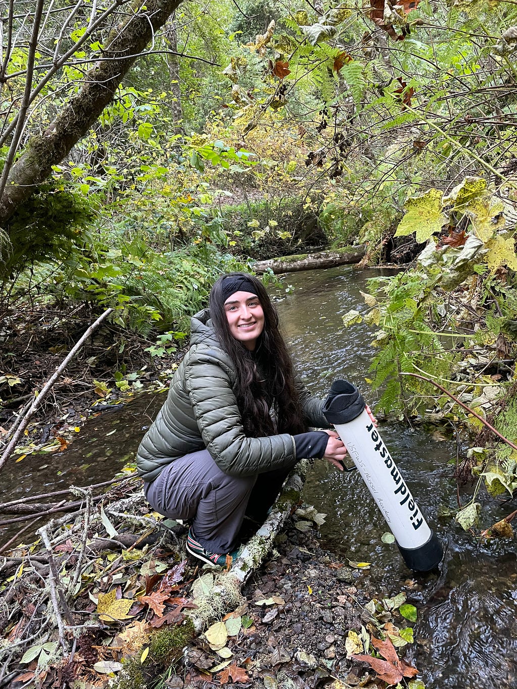 A smiling young woman in a creek bed doing a survey for mussels