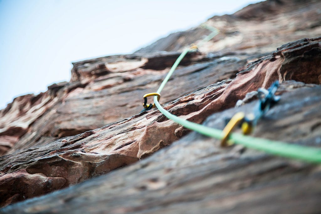 Cliff wall with rope leading upwards.