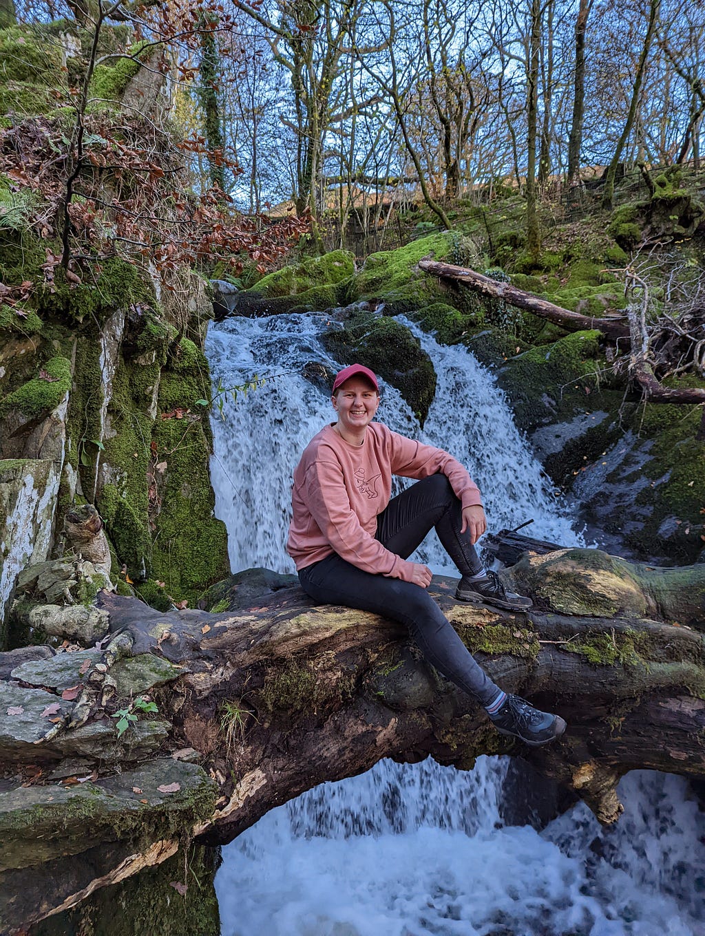 Sophie sat on a tree log in front of Stock Ghyll Force Waterfall