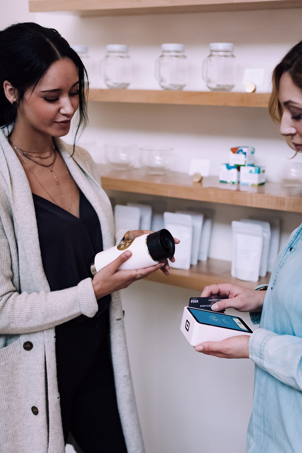 A photo of two women in a store, and one is paying for a product with a credit card.