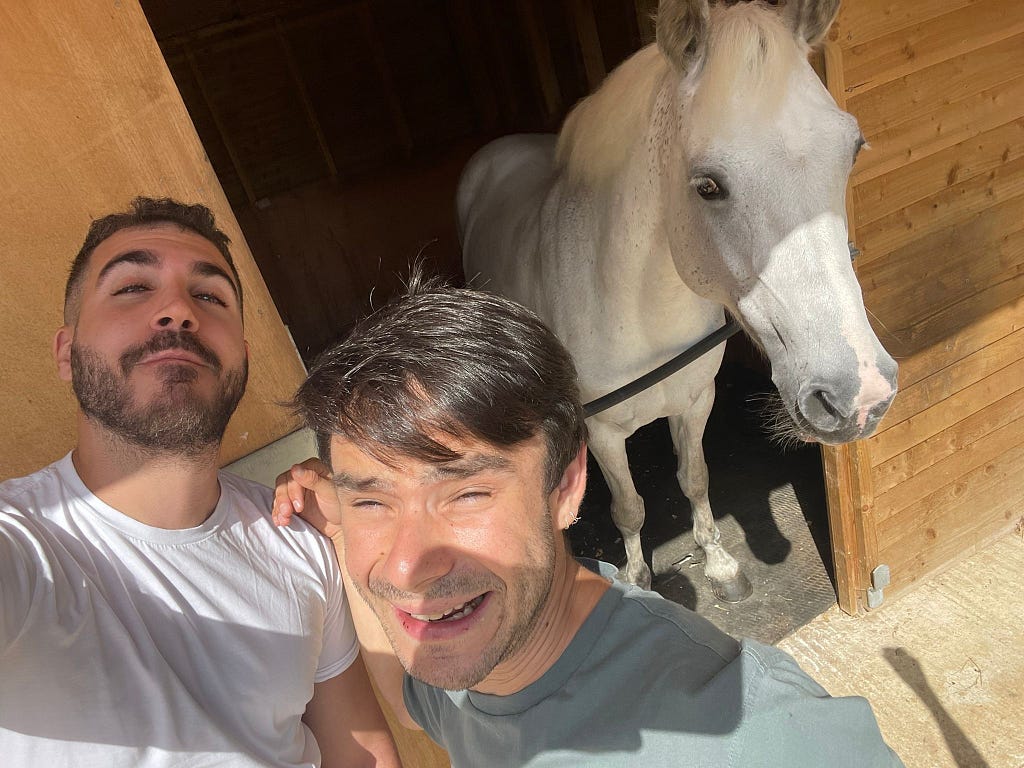 Two team members posing next to a white horse
