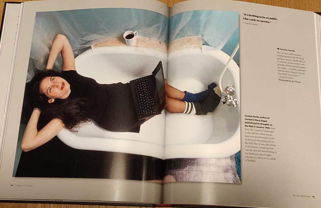 Woman sitting in a bathtub with a laptop
