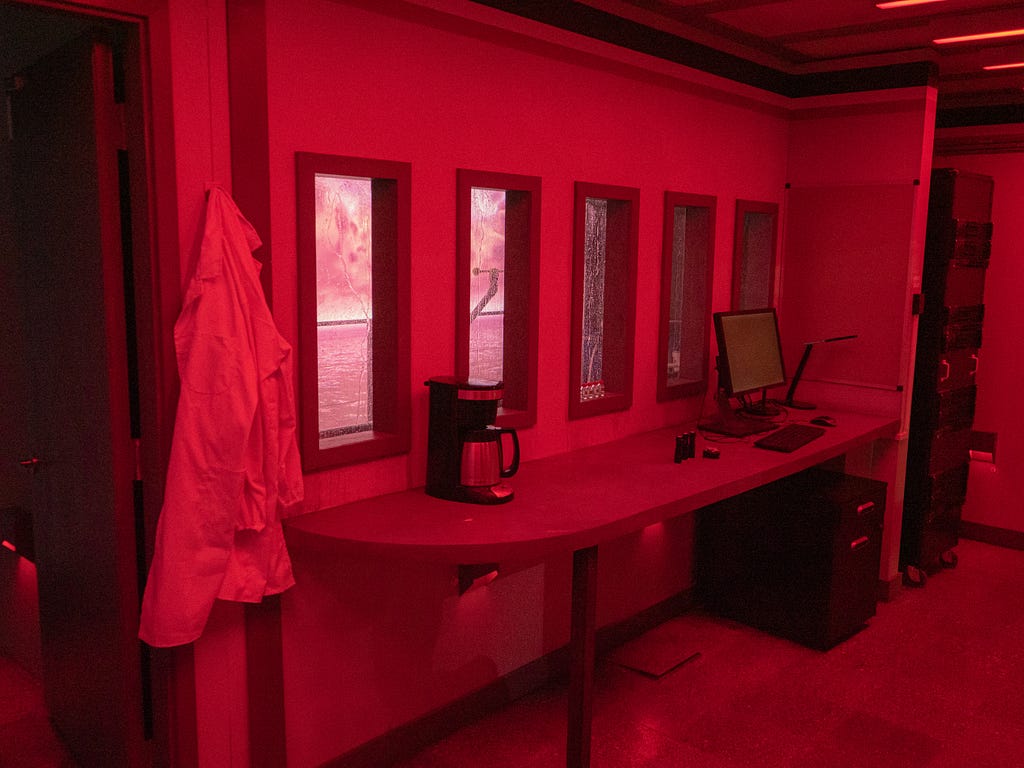 An escape room pod glows red with emergency lights during a hurricane at The University of Texas at Austin.