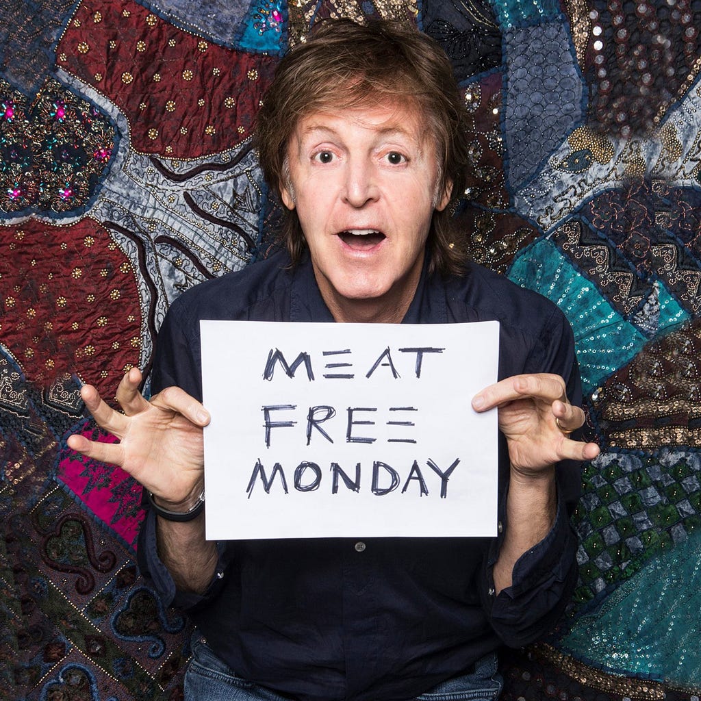 Foto do Paul McCartney (The Bleatles) segurando um cartaz escrito Meat Free Monday (Segunda Sem Carne).