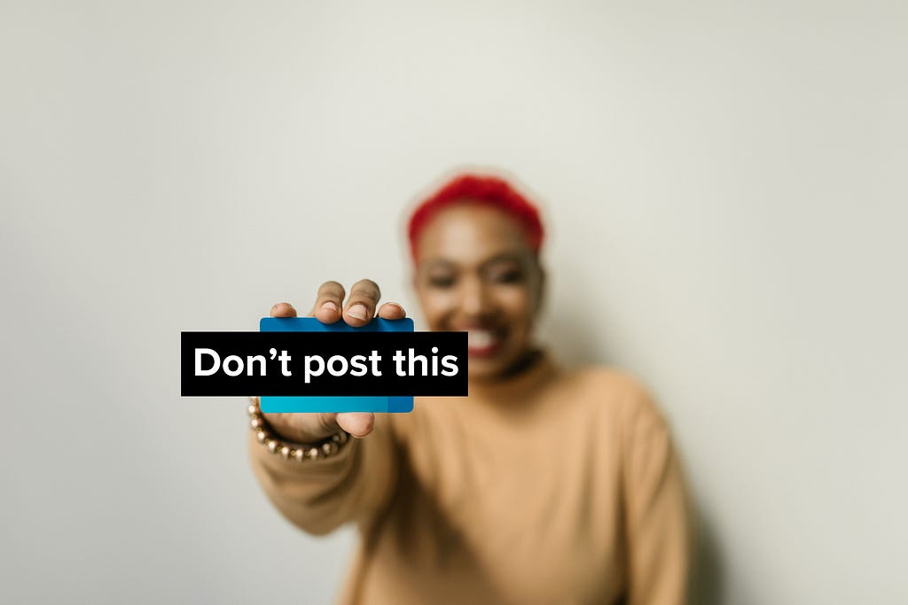 A person holds up a credit card in front of them. A title covers it that says, “Don’t post this”.