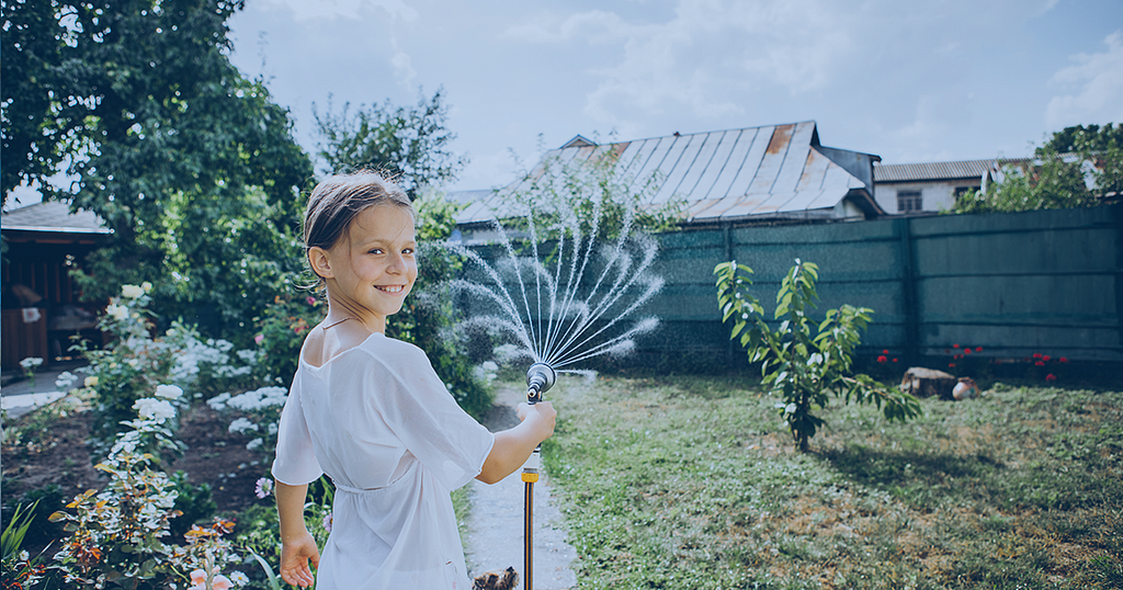 Picture of a young girl watering the garden using rainwater pumped from storage tanks