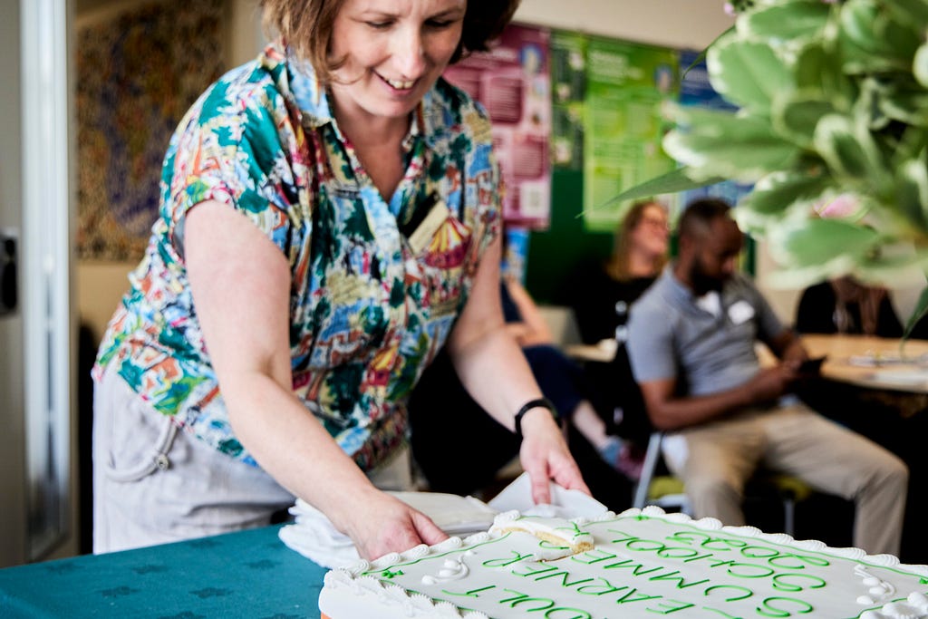 An image of LLC Development Officer Olivia Garvey cutting the celebration cake at the end of our Adult Learner Summer School.