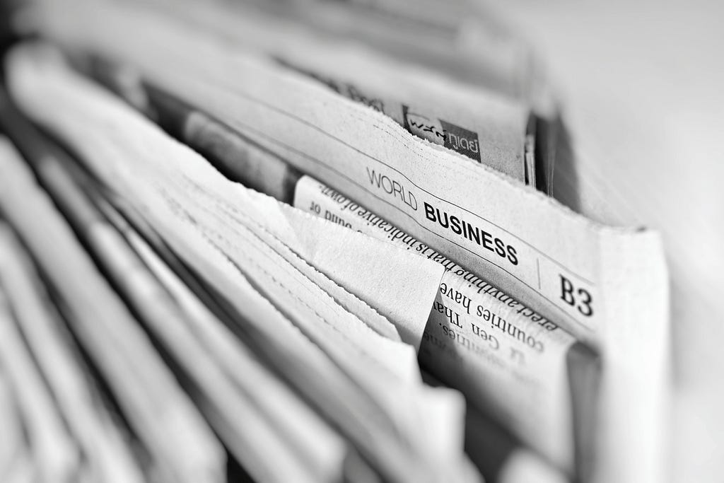 A set of broadsheet newspapers stacked horizontally with business section highlighted.