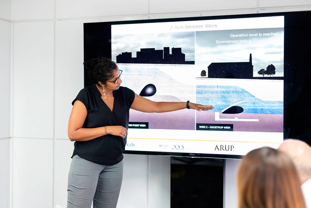 A woman presenting on a large screen in front of a small audience
