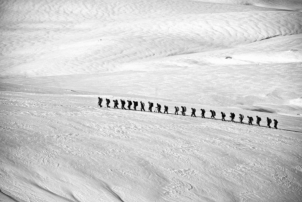 A group of people is hiking on snow dunes