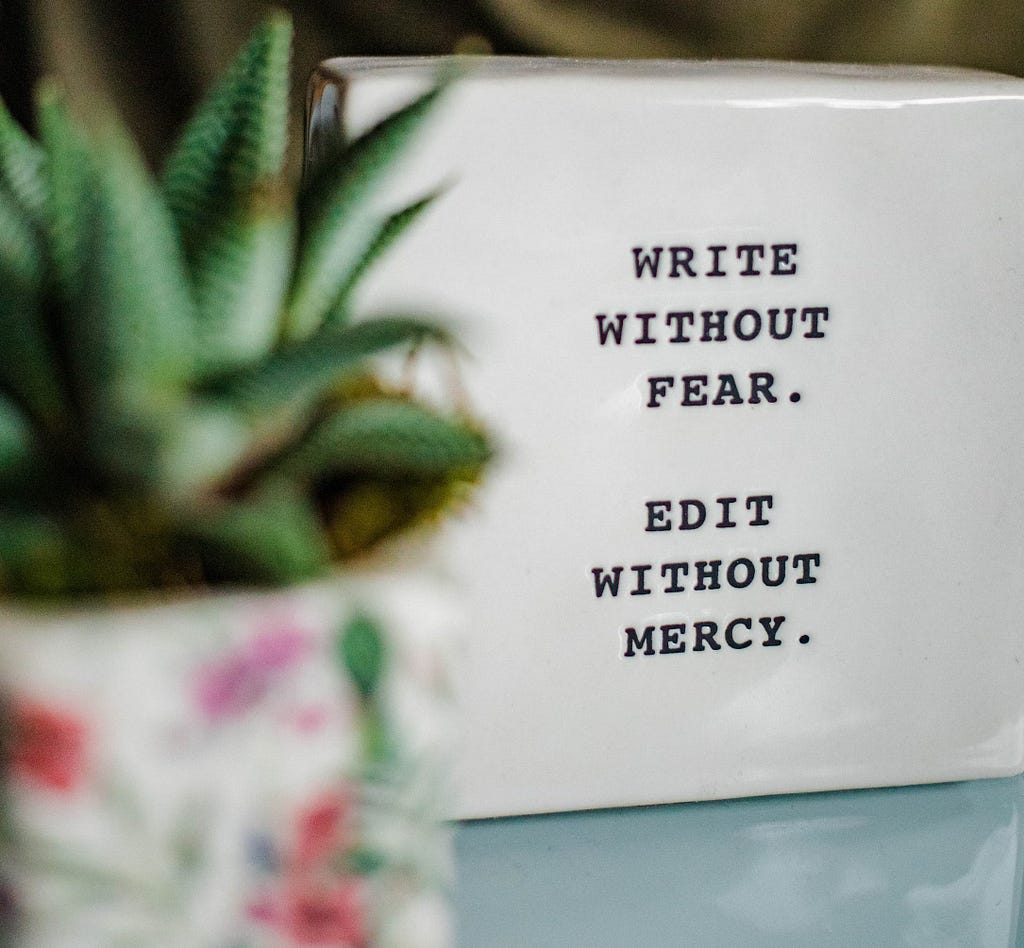 Sign on desk saying, “Write without fear. Edit without mercy.”