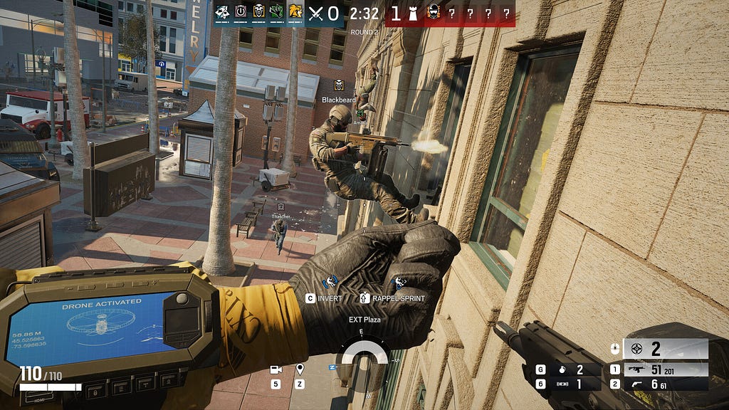 First-person view with HUD elements showing team status, timer, score, ammo, health, and interaction prompts, while a diegetic wrist-mounted device on the player’s hand displays an active drone interface integrated into the game world.
