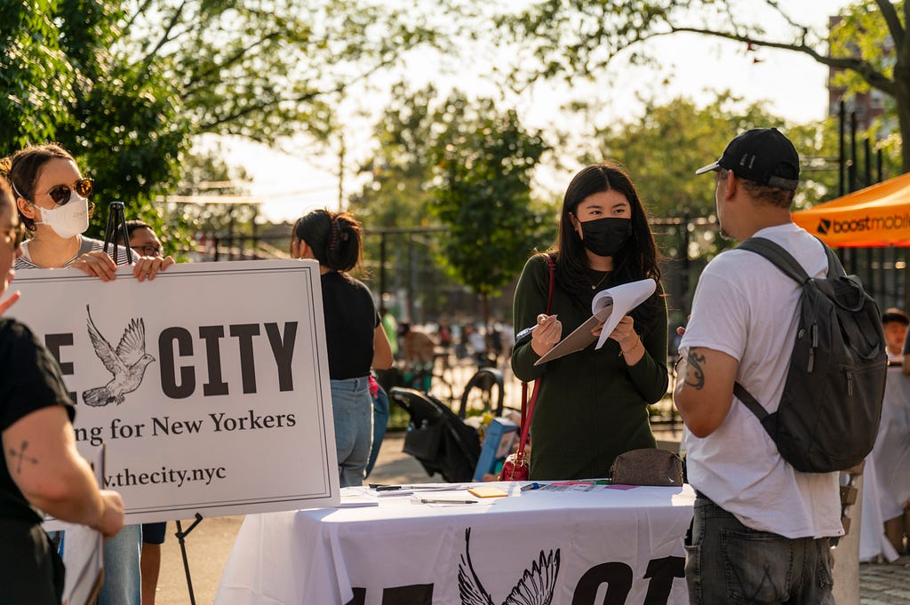 I (Sarah) reattach a sign for THE CITY at a community conversation event in Queens where residents, volunteers and staff disucss the ongoing impacts of the pandemic