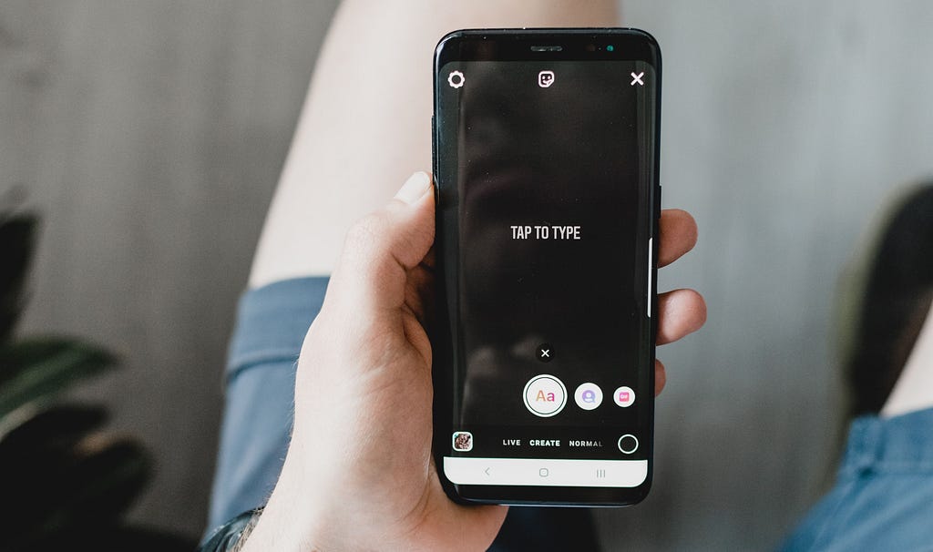 A person holding their phone preparing to put together a story on Instagram