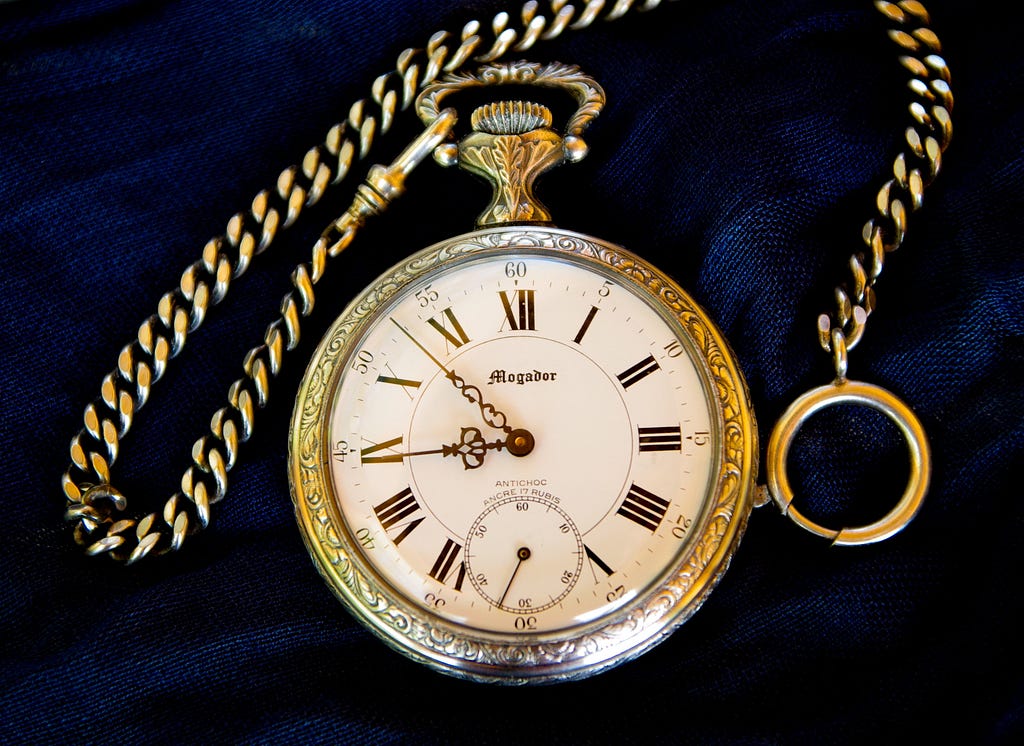 A gold stop watch on a navy blanket