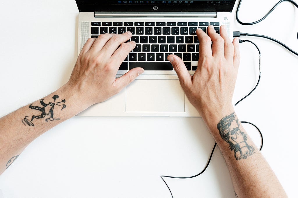 Hands tattooed on a keyboard