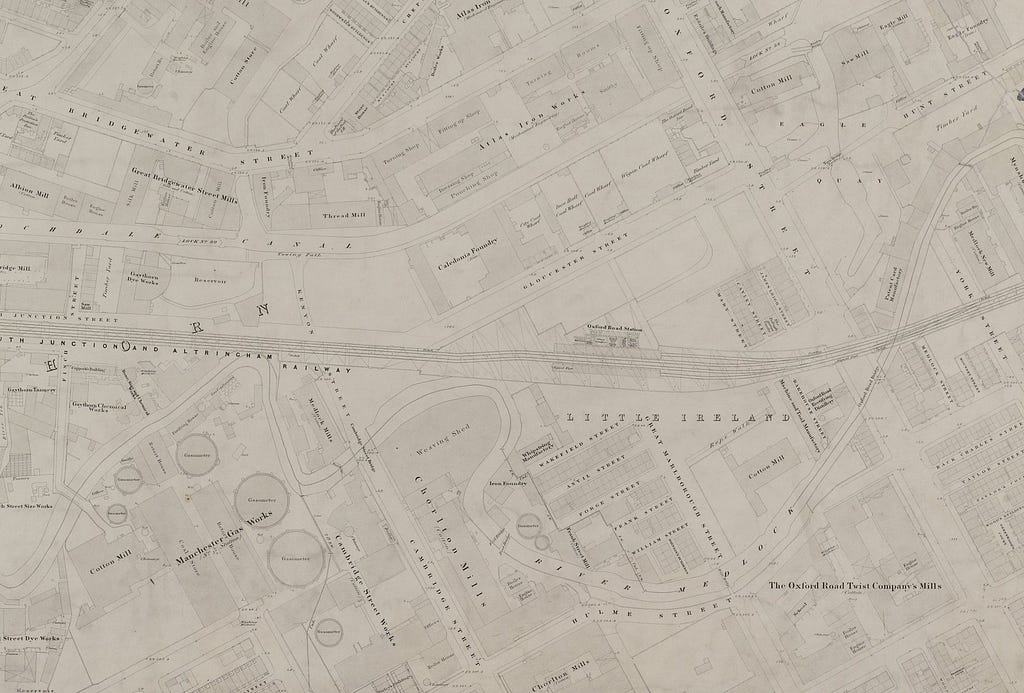 A detailed Ordnance Survey map identifying and naming the area known as Little Ireland in Chorlton-Upon-Medlock, Manchester. Back to back housing is shown in close proximity to a railway line, river, gas works and mills.