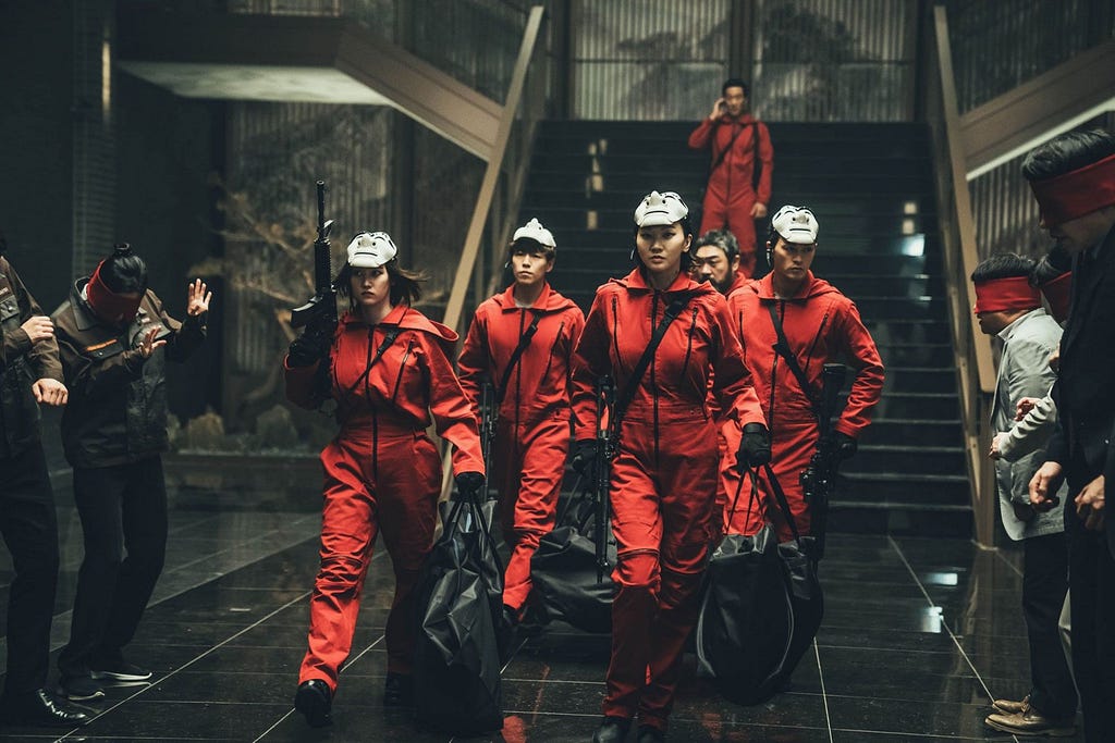 Armed robbers in red jumpsuits and Dali masks marching down stairs