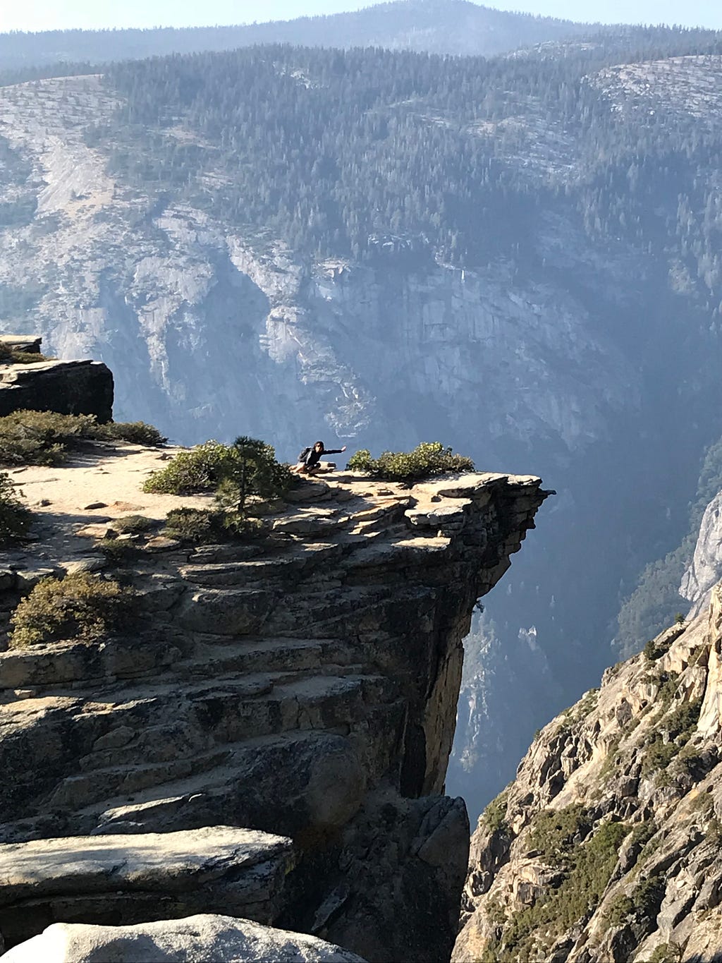 on my knees with one arm reaching out , near the edge of a big cliff in Yosemite