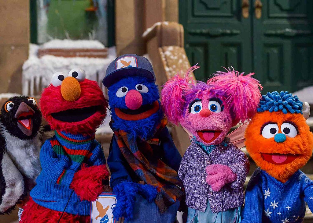 Five multi-coloured puppets standing on a snowy street