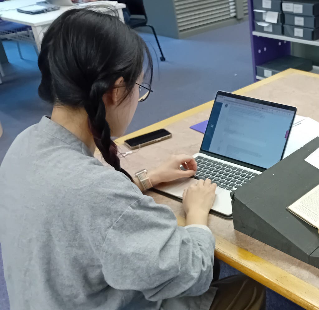 Yunqi He sitting at a desk, typing on a laptop