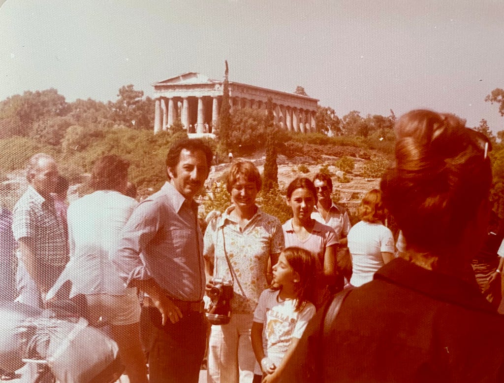 A family posing in front of a columned temple.