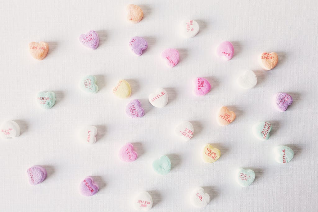 Scattered candy hearts with cute sayings written on them.
